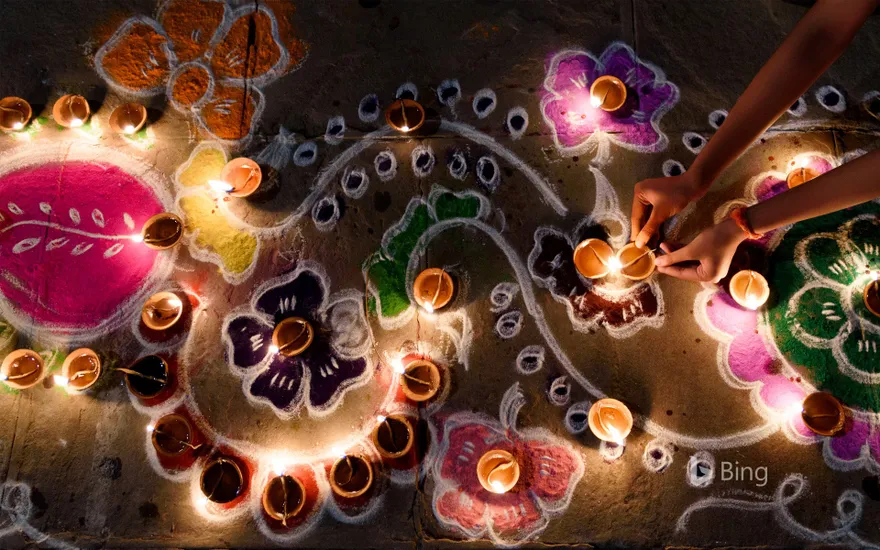 Oil lamps being arranged on rangoli during Diwali