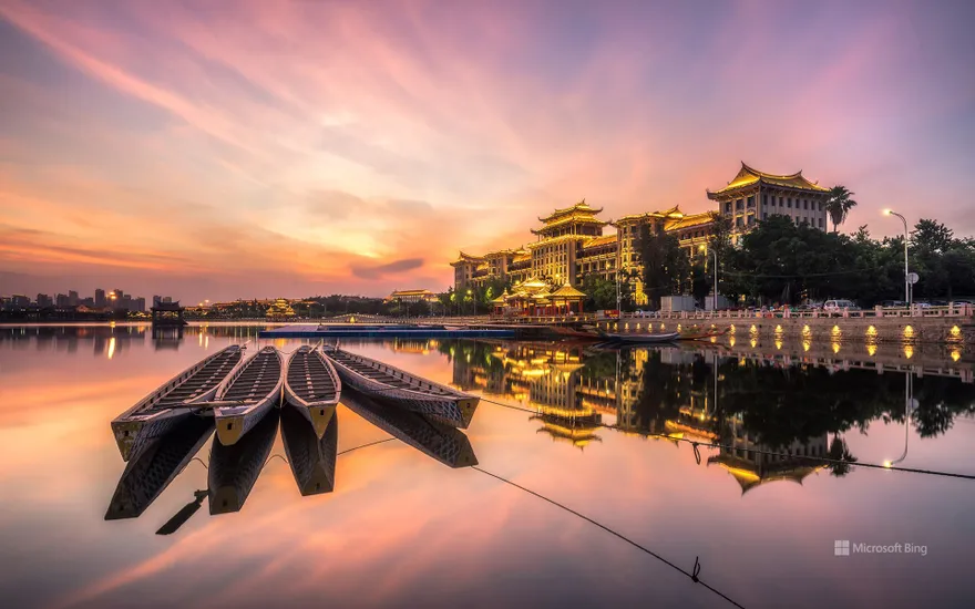 Xiamen Dragon Boat Pond in wide-angle lens, sunset light sprinkles on traditional dragon boats, China