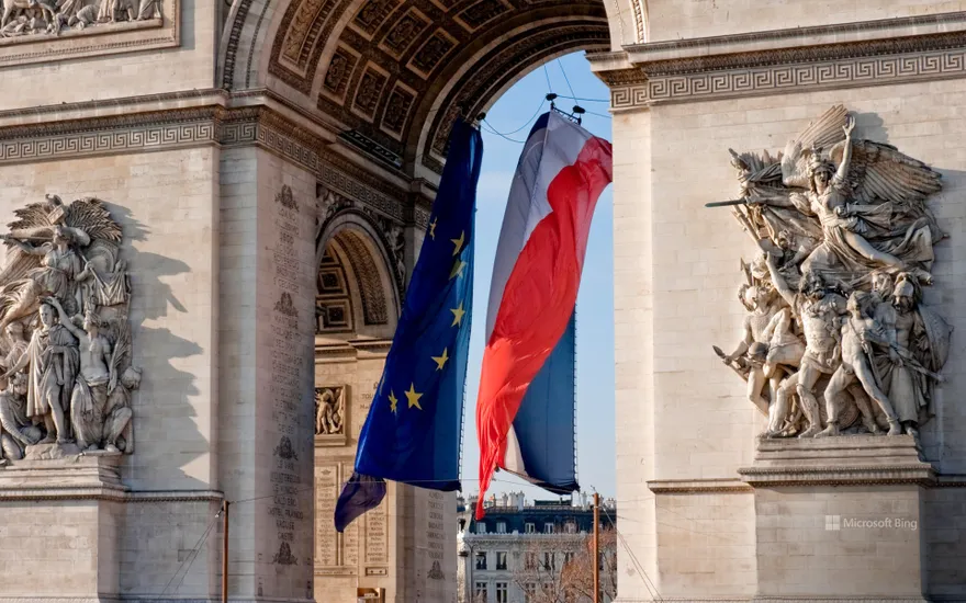 Flags of France and Europe fluttering under the Arc de Triomphe, Paris