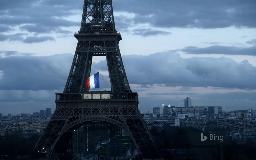 The French flag fluttering in the center of the Eiffel Tower on March 11, 2020, during a ceremony for the first National Day of Homage to Victims of Terrorism