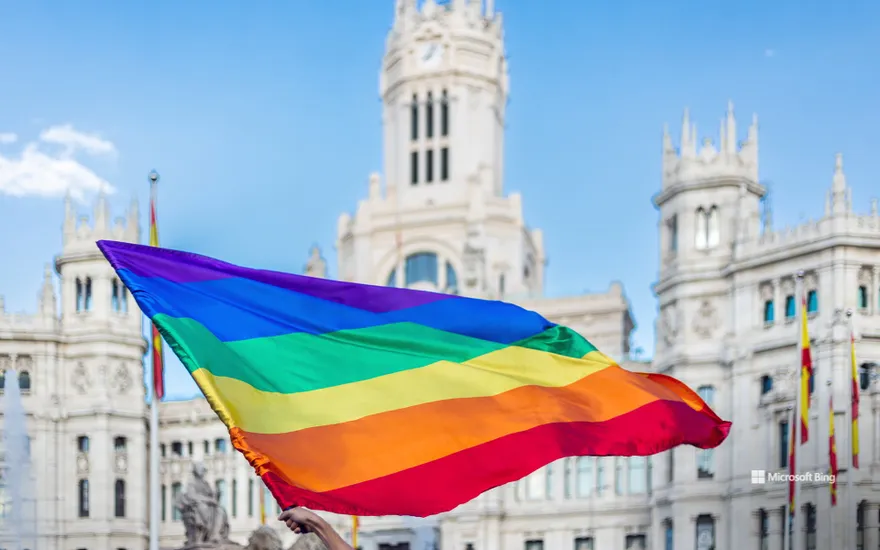 Arms waving the LGBTQIA flag at Plaza de Cibeles in Madrid, Spain