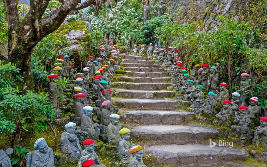 Small rakan statues line the stone pathway to the Daisho-in Temple, Miyajima, Japan