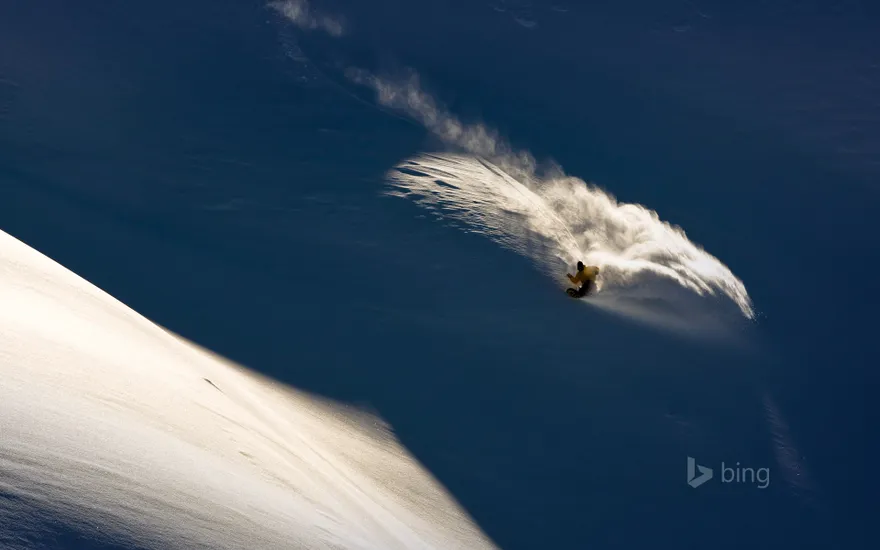 Snowboarder makes powder turn in backcountry terrain